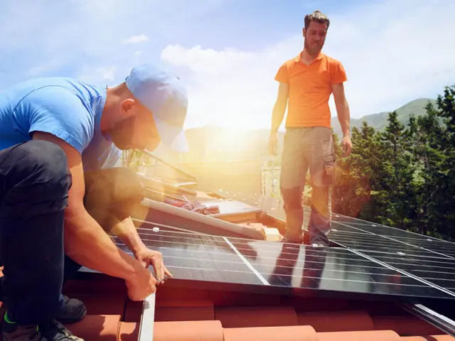 Mann montiert Solaranlage auf dem Dach